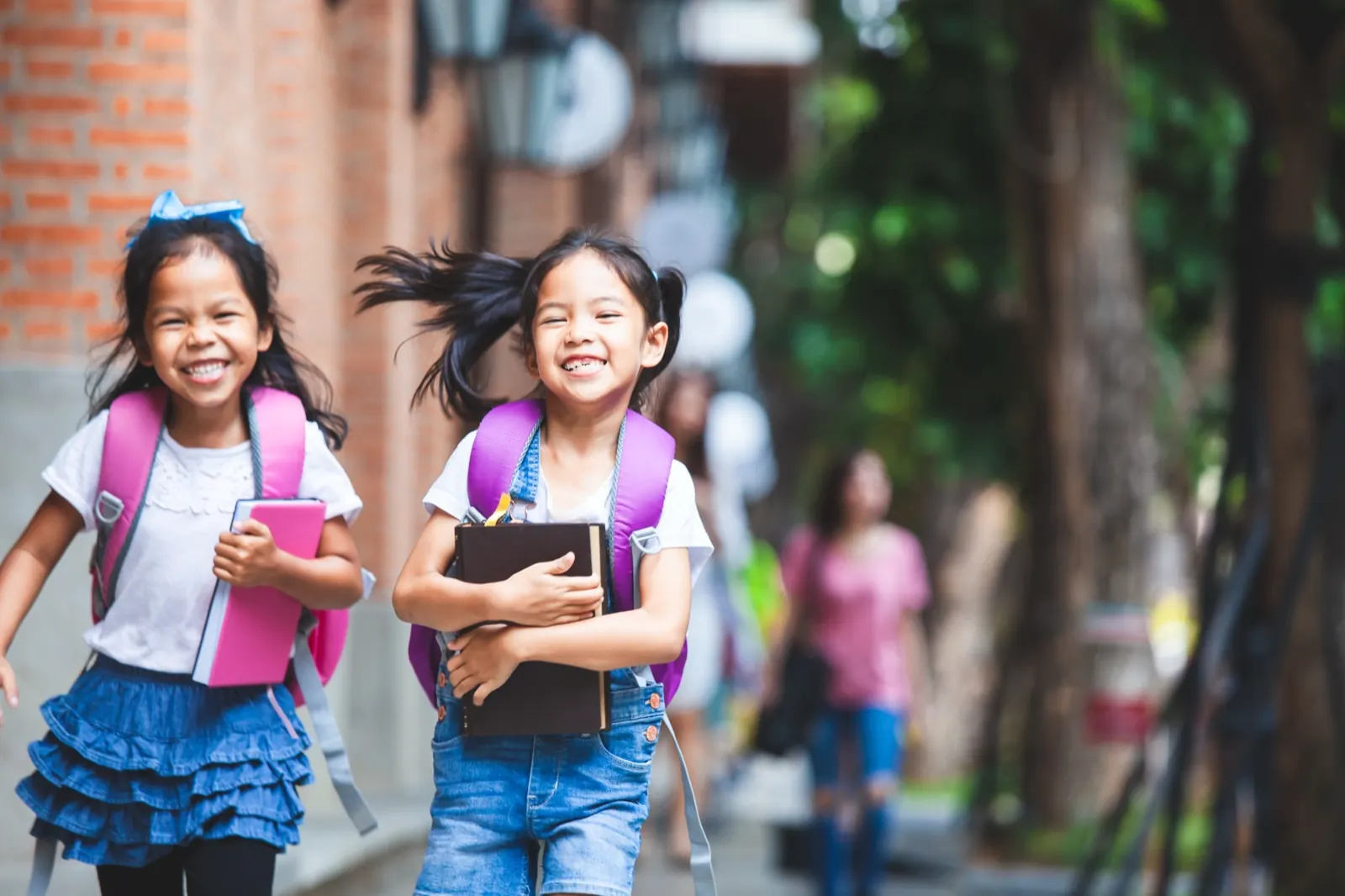リュックを背負い本を抱えて登校する女の子2人