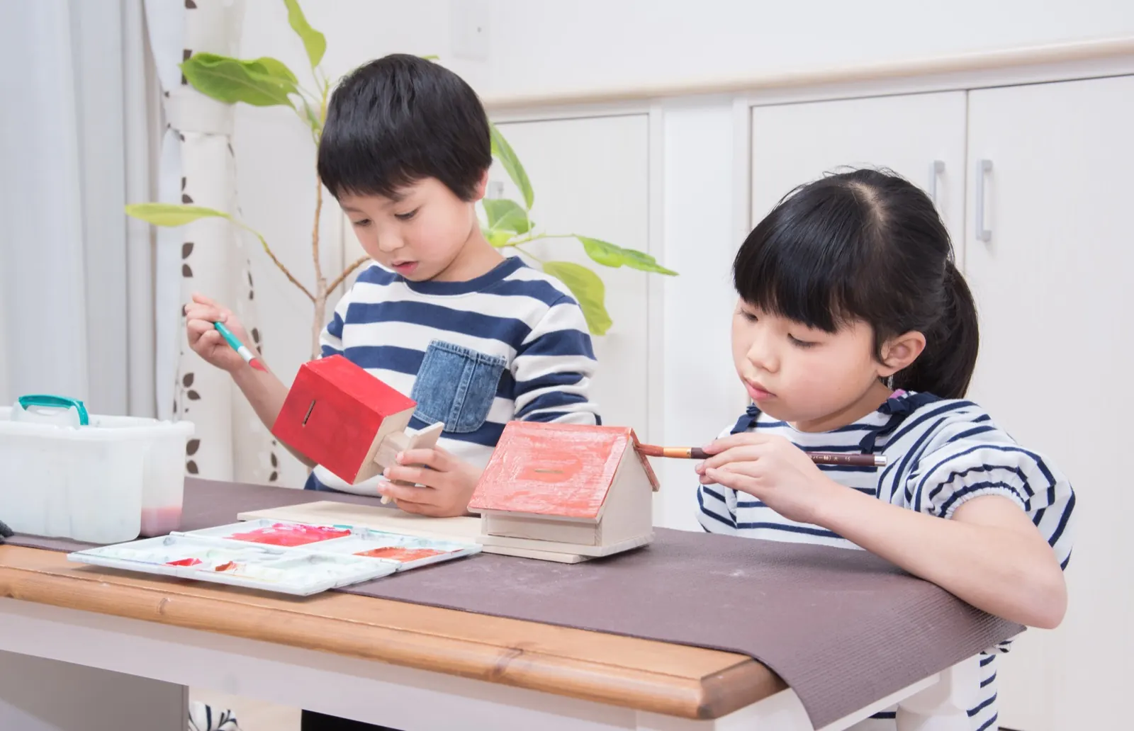 テーブルで工作をするきょうだい