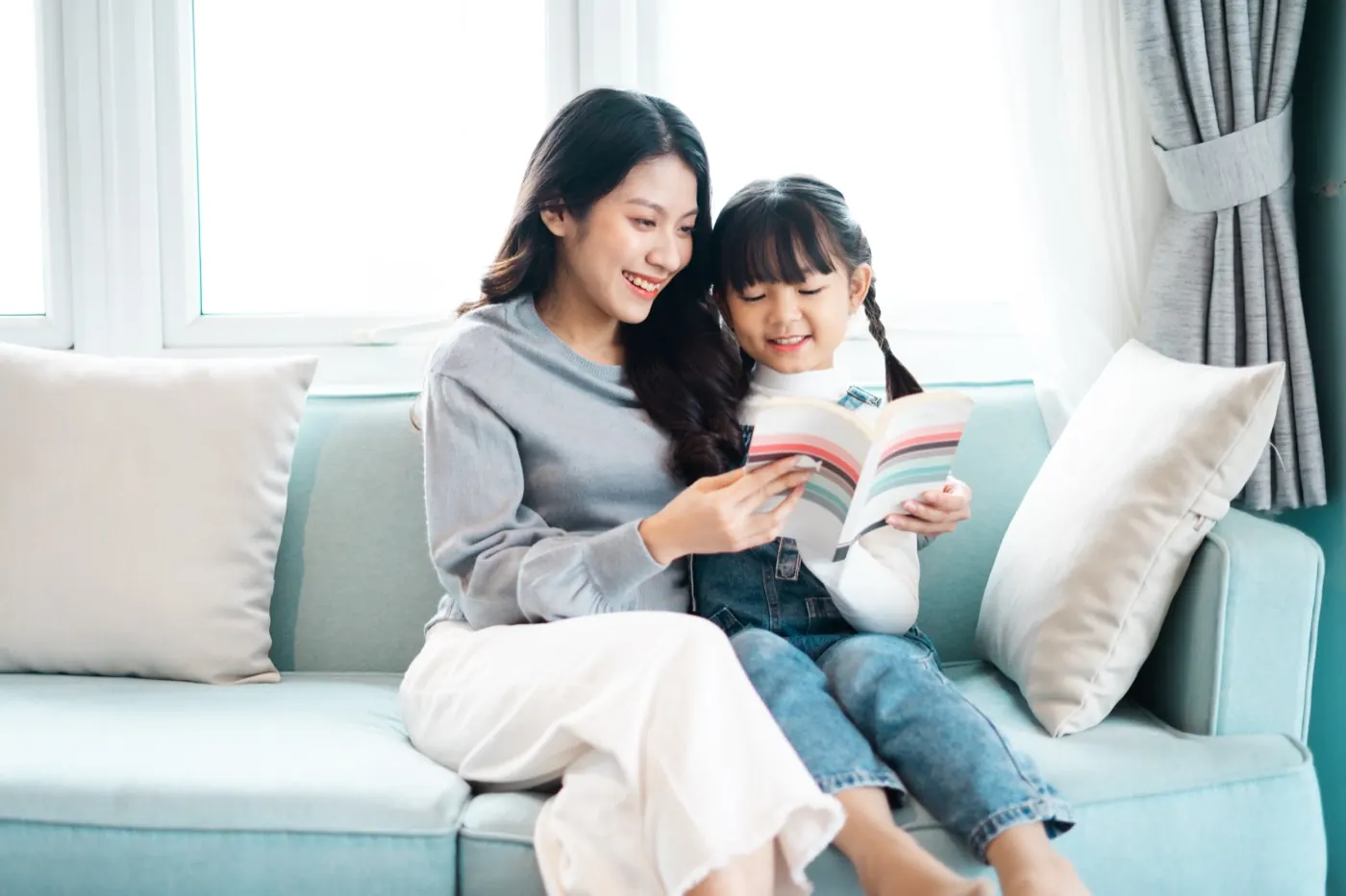 ソファに並んで本を読む母親と娘
