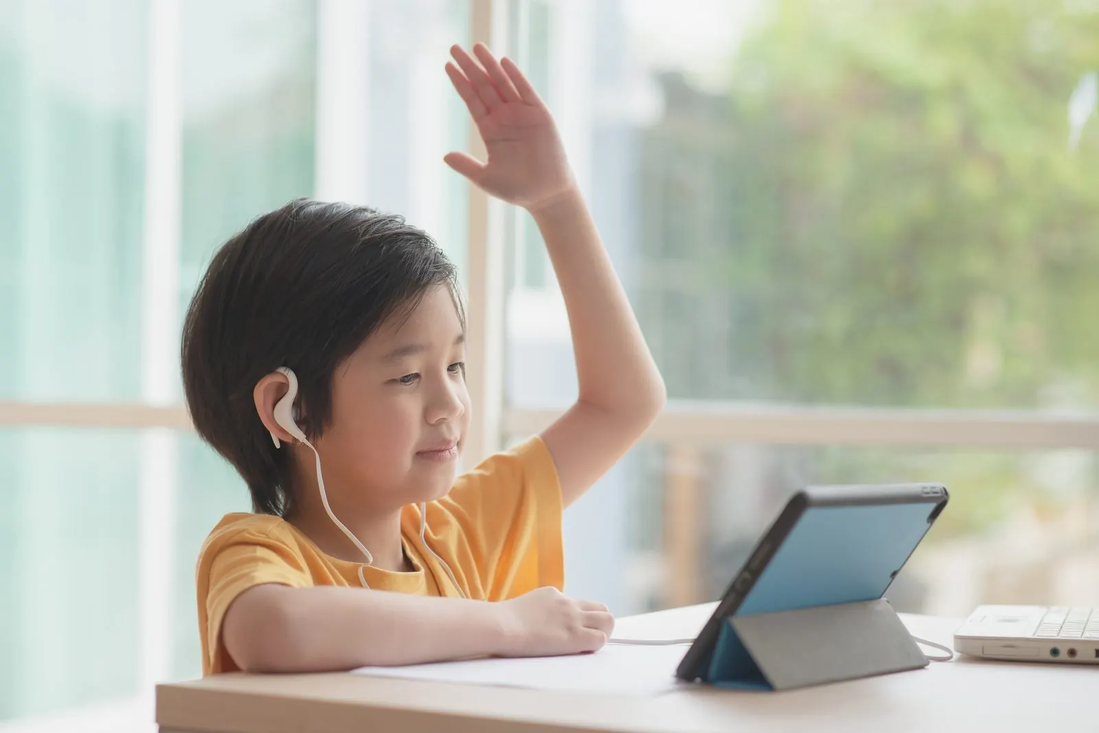 タブレットの画面に向かって手を挙げる男の子